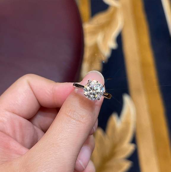 Gold solitaire ring with round cubic zirconia stone held in hand