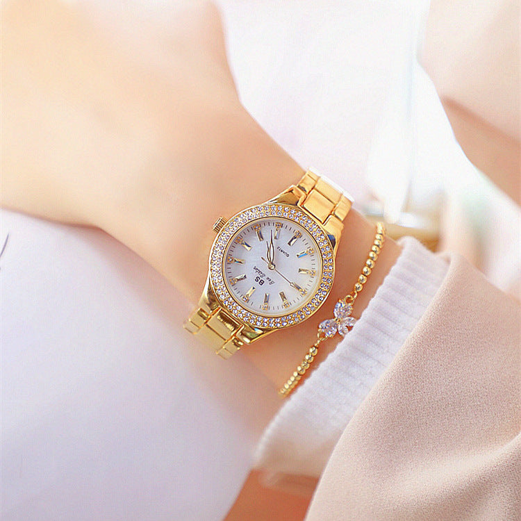 Gold tone watch with crystal bezel and link bracelet on wrist