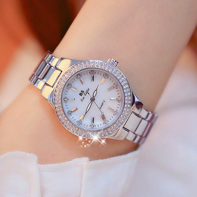 Gold tone watch with crystal bezel and link bracelet on wrist, view 4